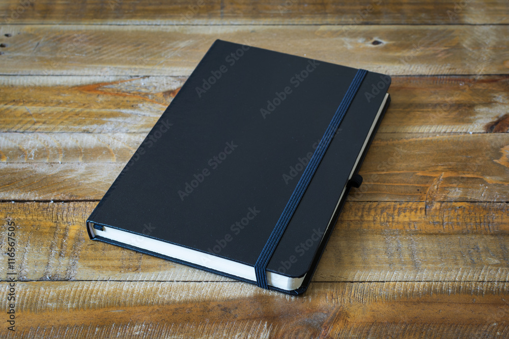 Black notebook on a wooden background Stock Photo | Adobe Stock