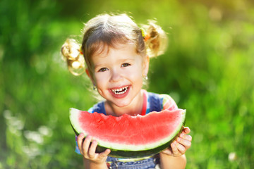 Happy child girl eats watermelon