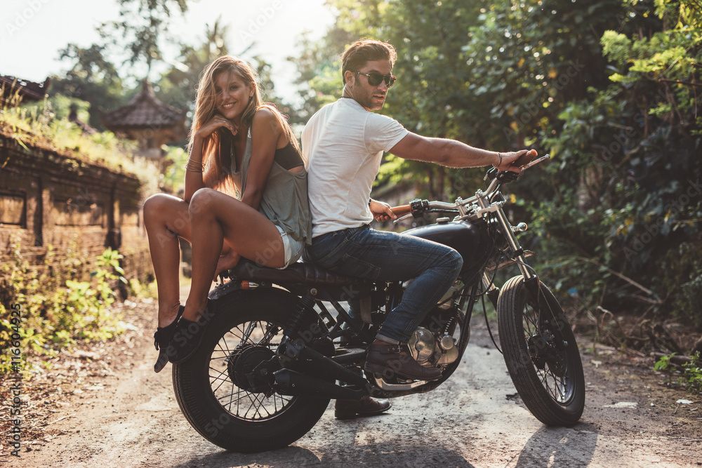 Beautiful young couple on a motorbike - obrazy, fototapety, plakaty 