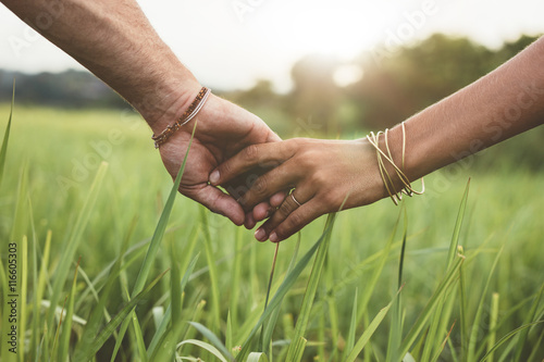 Fotomural Romantic couple holding hands in a field