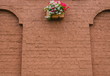 brick wall with a bed of flowers/on a wall from a brown brick the bed with flowers is attached
