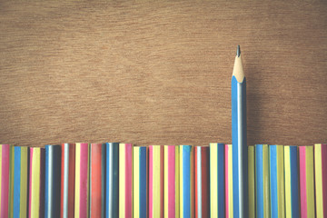 different businessman concept.blue pencil standing out from a bunch pencils on wooden floor. vintage