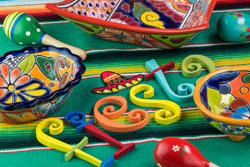 Mexican fiesta table decoration with  colorful painted letters, bright pottery, maracas.