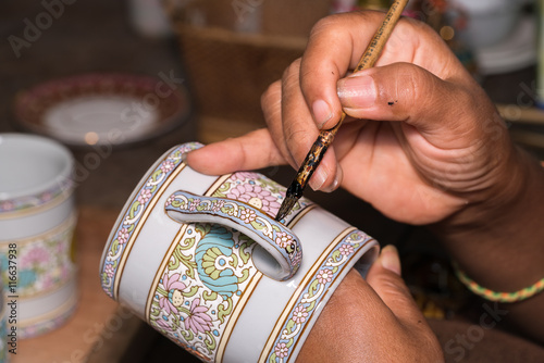 Fényképezés Female hands a brush painted a colorful ceramic cup handcraft