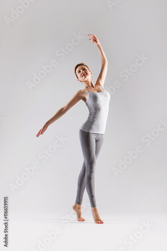 Leinwand Poster Beautiful young woman doing yoga on a gray studio background