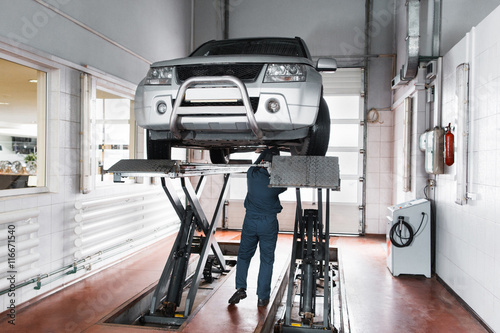 Fotografía Mechanic inspecting car suspension system of lifted automobile at repair service station