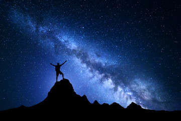 Wall Mural - landscape with milky way. blue night sky with stars and silhouette of a happy climber with backpack 
