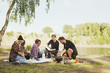© Astrakan Images - Multi-ethnic friends enjoying picnic at lakeshore