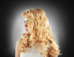 Wall Mural - Portrait of young woman with blonde hair on dark background