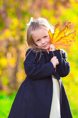 Wall Mural - Adorable little girl with autumn leaves in the beautiful park