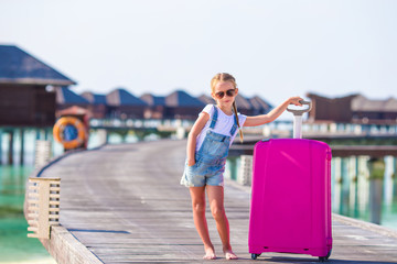 Little adorable girl with big luggage near water villa on Maldives