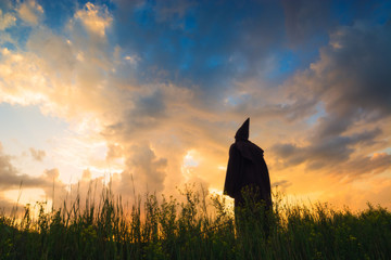 Monk on a hill against sunset sky