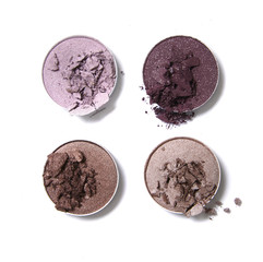 Broken neutral and pink toned eye shadow make up pots isolated on a white background