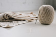 © Mint Images - A ball of string or thread and a metal crochet hook or needle with folded fabric.