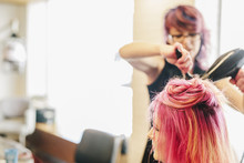 A Hair Stylist Blow-drying A Client's Long Pink Dyed Hair.