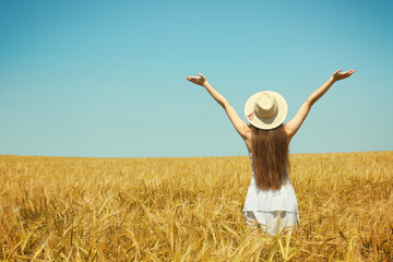 Wall Mural - Young woman enjoying nature and sunlight in wheat field