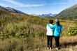 Mother and daughter looking at wild flowers with mountains 