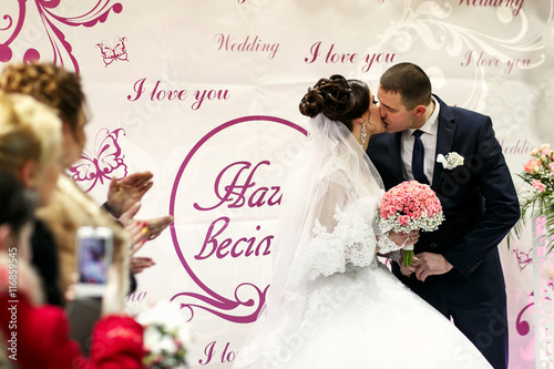 Photographie The brides kissing near wedding banner