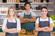© WavebreakmediaMicro - Smiling waiter and two waitresses standing with arms crossed