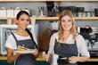 © WavebreakmediaMicro - Portrait of two waitresses holding plate of meal and coffee jug