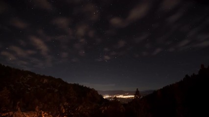 Wall Mural - Time Lapse of the stars moving across the night sky. Mountain and the lights from a small town can be seen at the bottom of the screen.