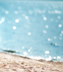 Fototapete - Blurred sea background with beautiful bokeh and sand on foreground