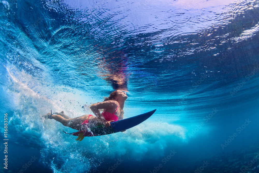 Young active girl wearing bikini in action - surfer with surf board dive underwater under big ocean wave. Family lifestyle, people water sport adventure camp and beach extreme swim on summer vacation. - obrazy, fototapety, plakaty 