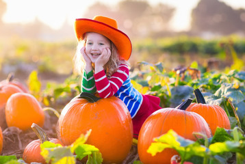 child playing on pumpkin patch