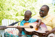 © digitalskillet1 - African American man teaching his son how to play the guitar