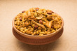 Traditional indian deep fried salty dish - chivda or mixture or farsan or farsaan made of gram flour and mixed with dry fruits in teracotta bowl, artistic background. top angle, closeup, isolated