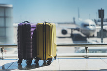 Two Suitcases In The Airport Departure Lounge, Airplane In The Blurred Background, Summer Vacation Concept, Traveler Suitcases In Airport Terminal Waiting Area