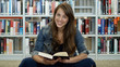 © kiorafilms - A young woman in a public library. It's her leisure time and she is looking for some good books to read.