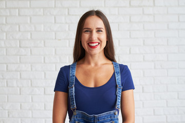 Wall Mural - Young smiling woman standing against a wall