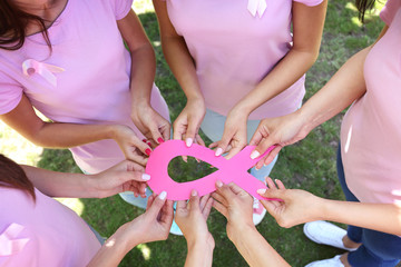 Wall Mural - Female hands holding pink ribbon together. Breast cancer concept