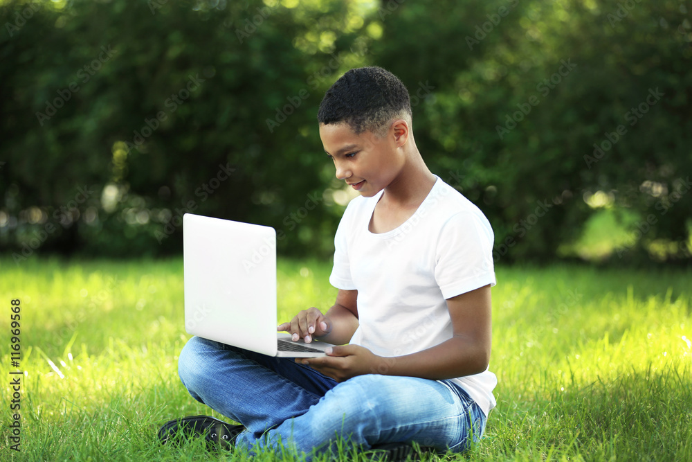 African American boy with laptop in park