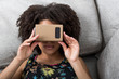 Young woman using virtual reality device cardboard vr on sofa