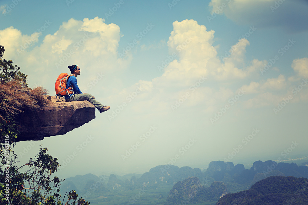successful woman backpacker sit on mountain peak cliff - obrazy, fototapety, plakaty 