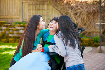 Wall Mural - Disabled boy in wheelchair laughing with teen sister on patio