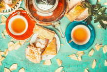 Nice Tea Brunch Scene With Colorful Cup Of Tea, Tea Pot , Cakes And Flowers On Turquoise Shabby Chic Background, Top View