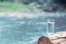 Glass Of Water On Blurred River Background
