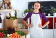 © shefkate - Young woman standing in her kitchen near desk
