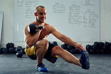 Wall Mural - Happy athlete doing one leg situps with kettlebell at the gym