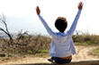 © mimagephotos - Young female on wooden log with hands raised