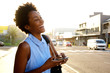 © mimagephotos - Cheerful young woman with mobile phone on the city street