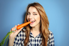 Beautiful Girl Eating Carrot On Blue Background