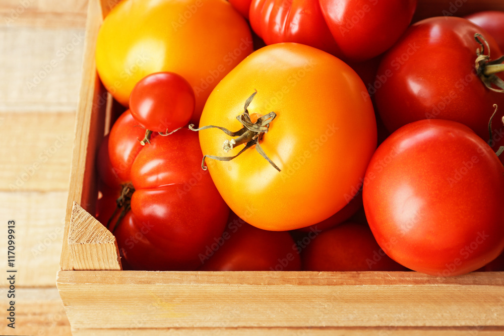 Different tomatoes in wooden box, close up