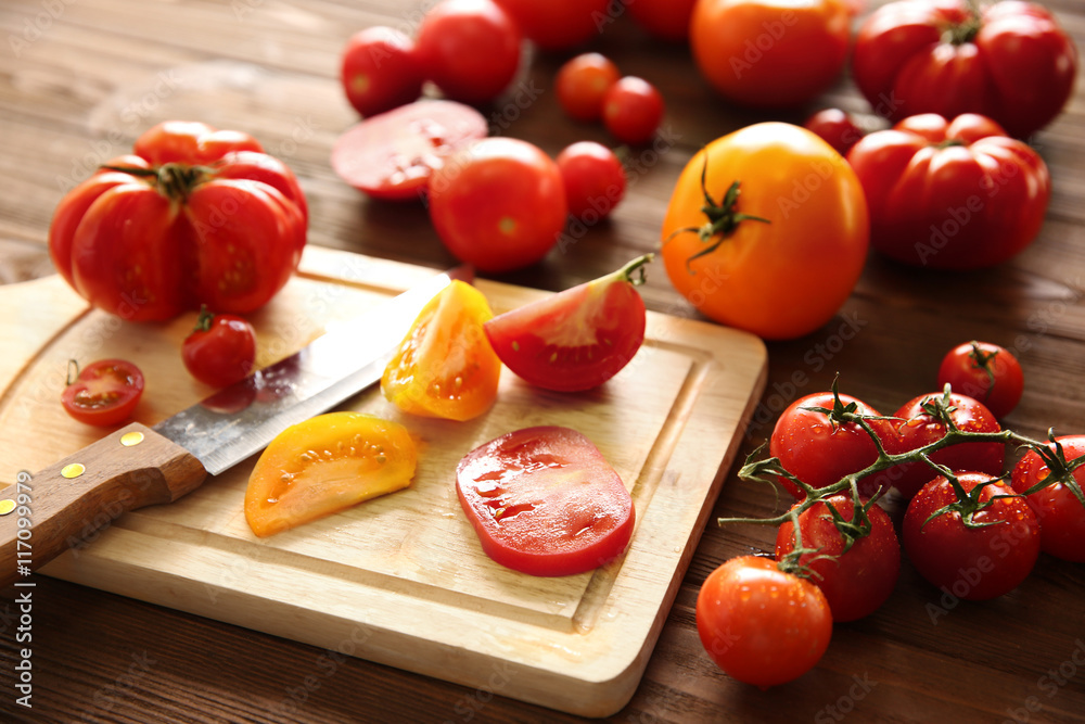 Composition of tomatoes and slices on wooden cutting board