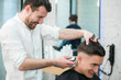 © romankosolapov - Professional styling. Close up side view of young satisfied man getting haircut by hairdresser with electric razor at barbershop