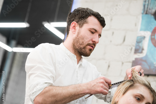 Hairdresser cutting client's hair in salon with electric razor closeup Slika na platnu