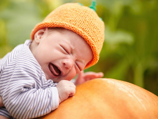 Fototapete - baby with pumpkin hat sleeping on big orange pumpkin